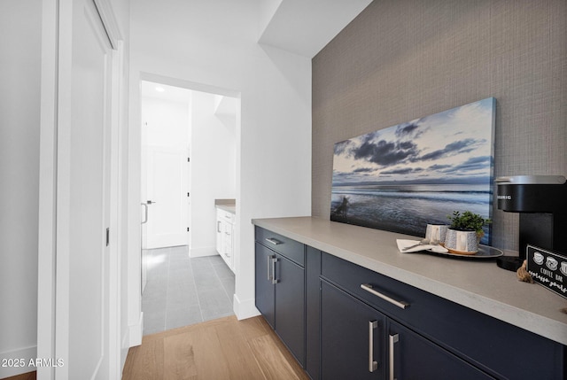 interior space with light wood-type flooring, wallpapered walls, an accent wall, and baseboards