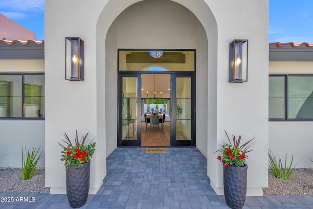 view of exterior entry with a tile roof and stucco siding
