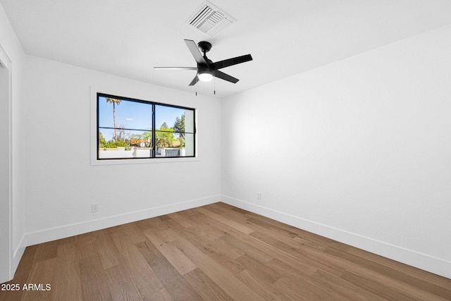spare room featuring visible vents, baseboards, a ceiling fan, and wood finished floors