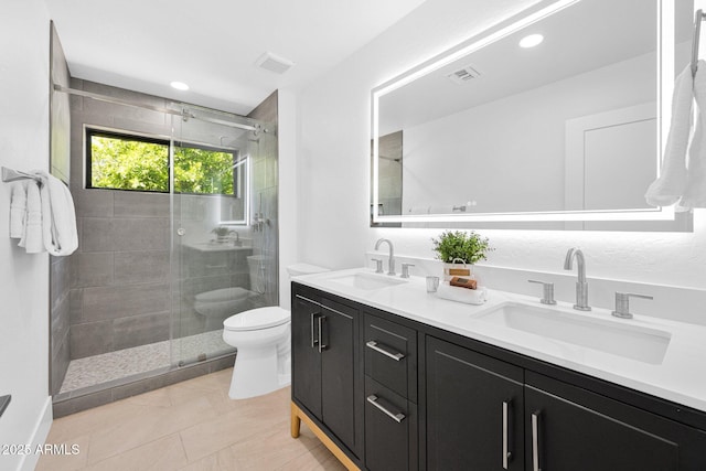 bathroom with a sink, toilet, a shower stall, and double vanity