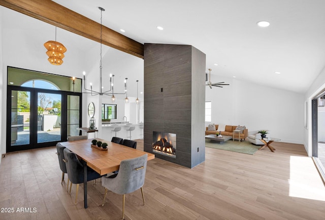 dining room featuring high vaulted ceiling, a notable chandelier, light wood-style floors, and beamed ceiling