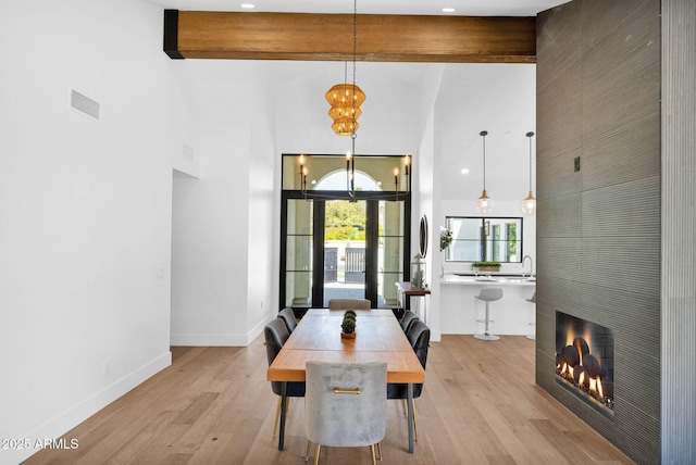 dining area with beamed ceiling, visible vents, a high ceiling, light wood finished floors, and baseboards