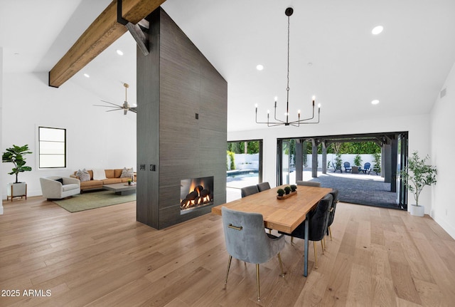 dining area with high vaulted ceiling, beamed ceiling, light wood-type flooring, a tiled fireplace, and plenty of natural light