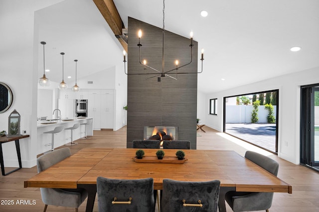 dining area with beam ceiling, high vaulted ceiling, light wood-type flooring, and a chandelier