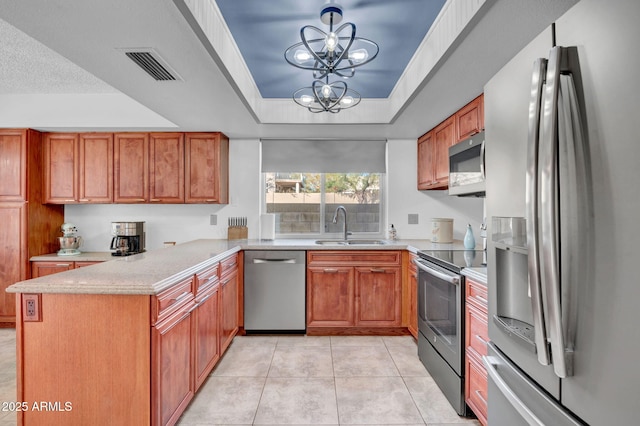 kitchen featuring stainless steel appliances, a peninsula, a sink, visible vents, and a raised ceiling