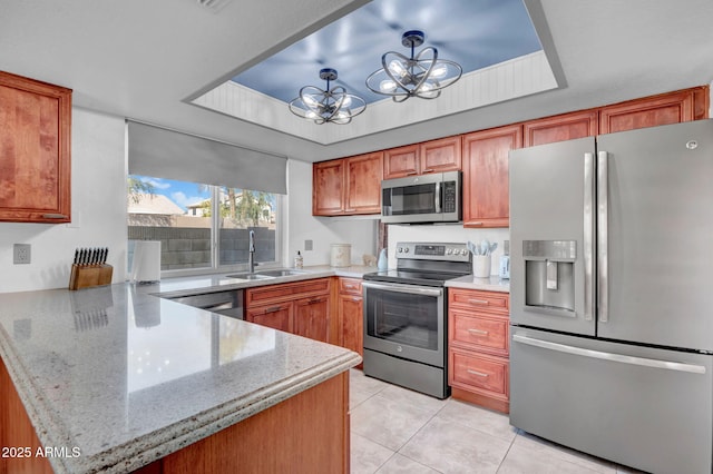 kitchen featuring a notable chandelier, stainless steel appliances, a raised ceiling, a sink, and a peninsula