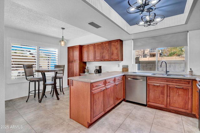 kitchen featuring a tray ceiling, brown cabinets, stainless steel dishwasher, a sink, and a peninsula