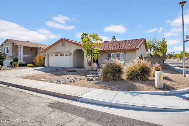 mediterranean / spanish-style home featuring an attached garage, driveway, a tiled roof, and stucco siding