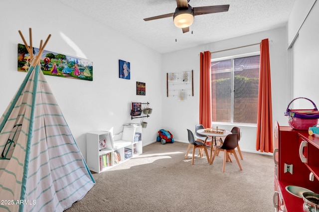 playroom with a textured ceiling, carpet, a ceiling fan, and baseboards