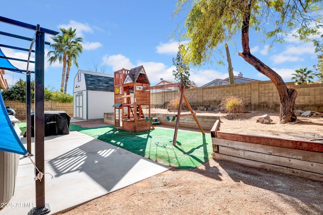 view of play area with an outbuilding, a shed, a patio area, and a fenced backyard