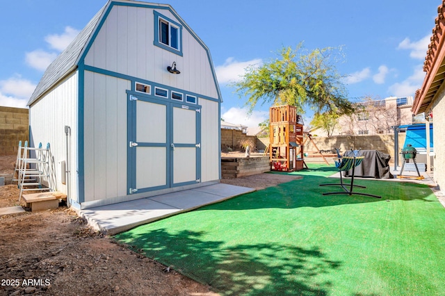 view of shed featuring a playground and a fenced backyard