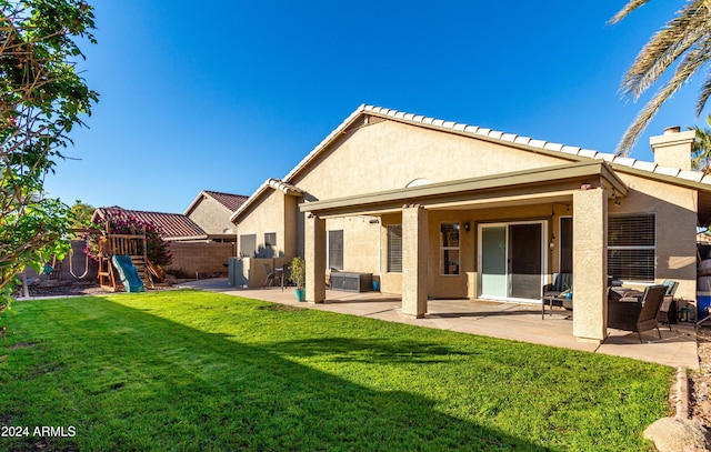 rear view of property featuring a patio area, a playground, and a yard