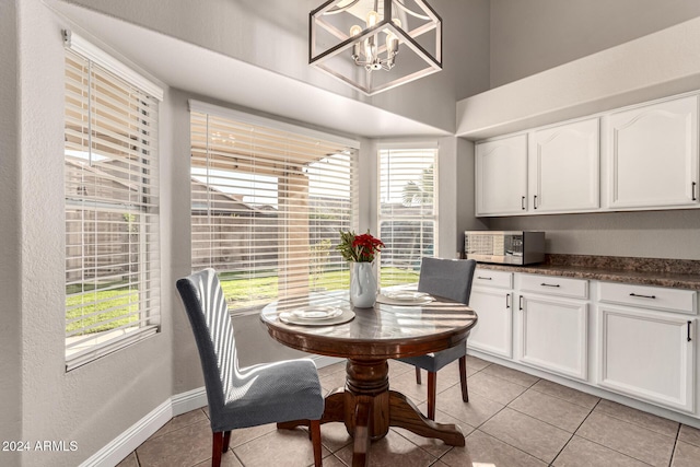 tiled dining space featuring plenty of natural light and an inviting chandelier