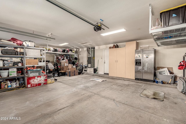 garage with stainless steel fridge with ice dispenser and a garage door opener