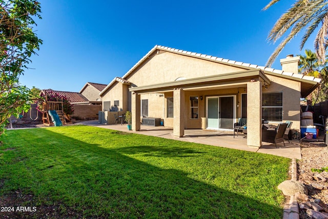 rear view of house with a playground, a lawn, and a patio