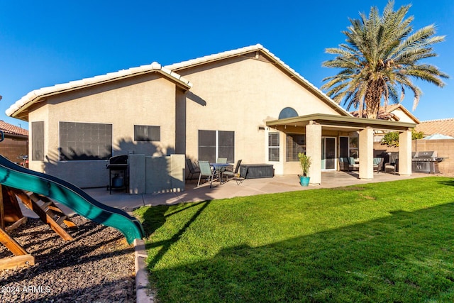 rear view of house featuring a yard, a playground, and a patio area