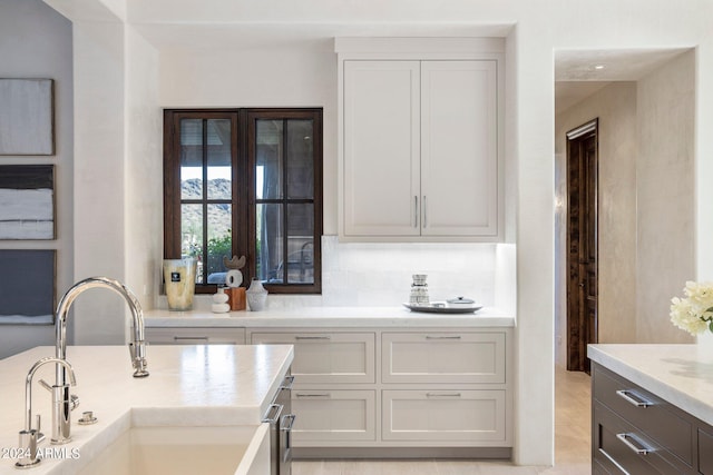 kitchen with sink, light tile floors, and light stone counters