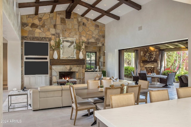 dining room with high vaulted ceiling, plenty of natural light, a stone fireplace, and beam ceiling