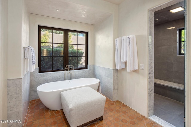 bathroom with tile flooring, tile walls, and a bathtub