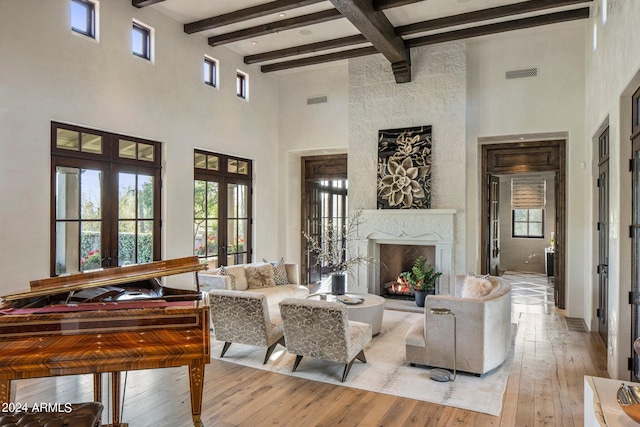 living room featuring beamed ceiling, french doors, light hardwood / wood-style floors, and a high end fireplace