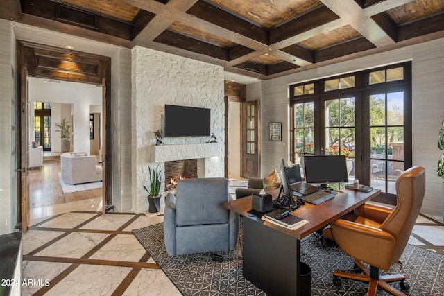 office area with coffered ceiling, a stone fireplace, and plenty of natural light