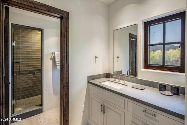 bathroom with a shower with door, tile floors, and vanity