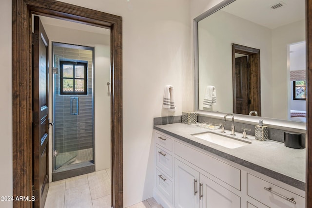 bathroom featuring vanity with extensive cabinet space, tile floors, and a shower with shower door