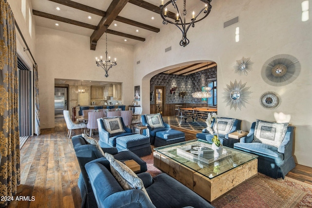 living room with a notable chandelier, hardwood / wood-style floors, a high ceiling, and beam ceiling