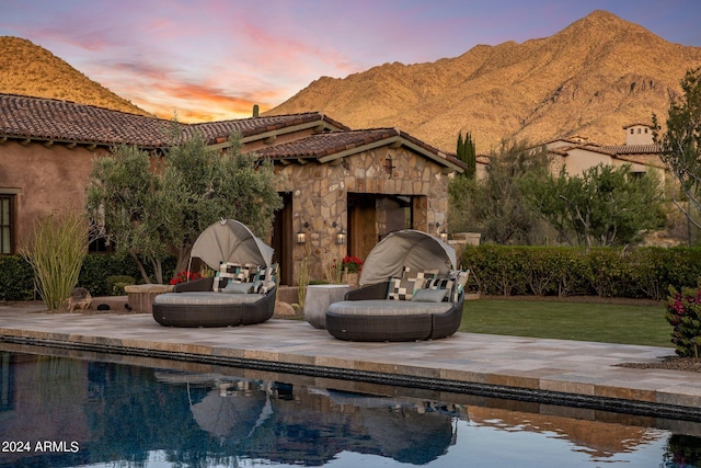 view of front facade with an outdoor stone fireplace, a mountain view, a yard, and a patio