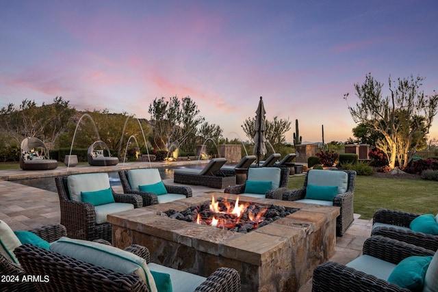 patio terrace at dusk with an outdoor fire pit and a lawn