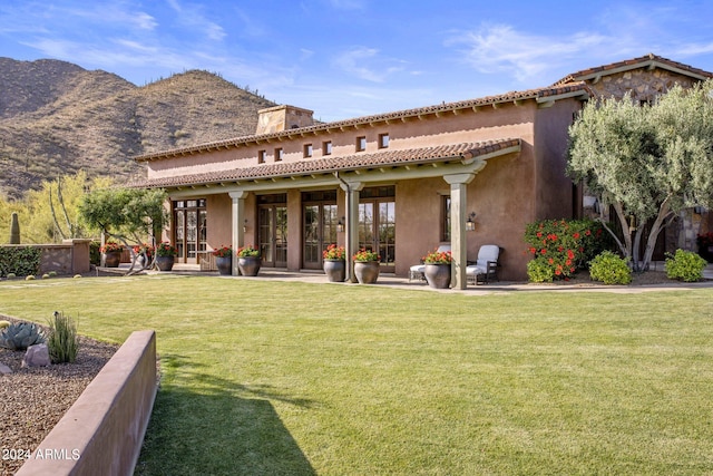 rear view of house featuring a mountain view, a yard, and french doors