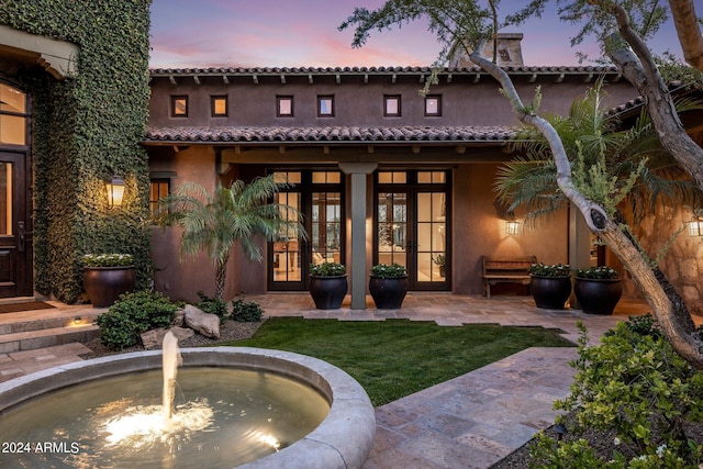 back house at dusk featuring french doors