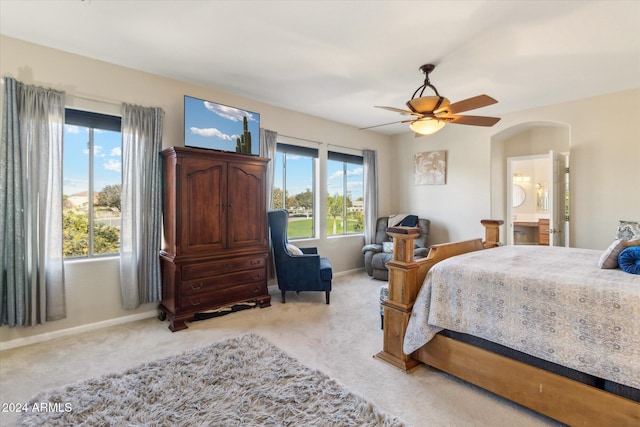 carpeted bedroom featuring ceiling fan, multiple windows, and ensuite bath