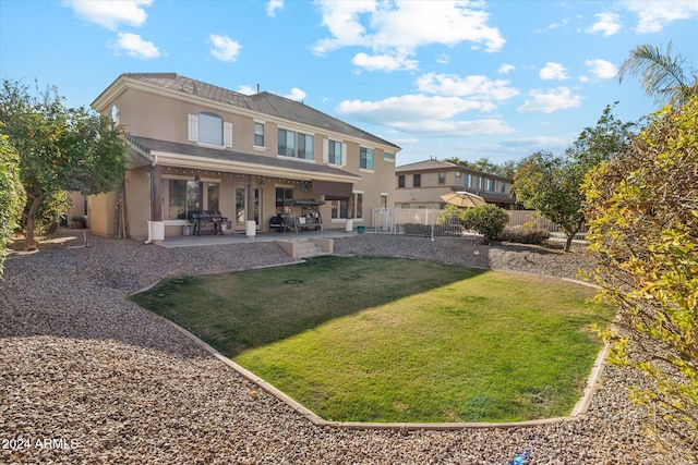 rear view of house featuring a lawn and a patio area