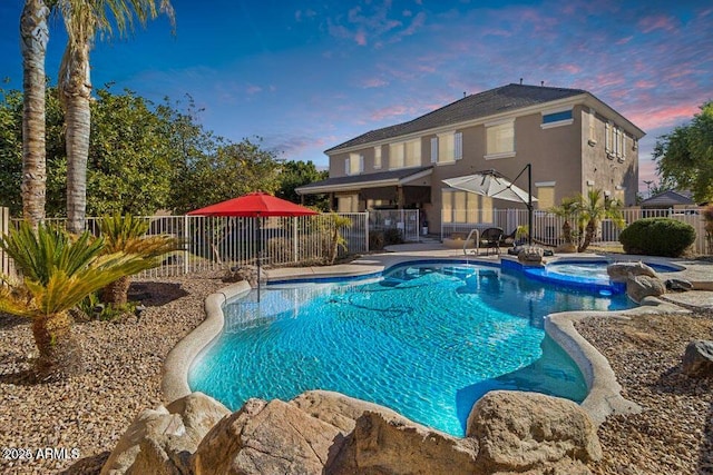 pool at dusk featuring an in ground hot tub and a patio