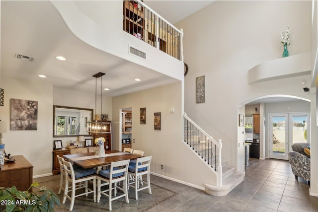 tiled dining room featuring a towering ceiling and a notable chandelier