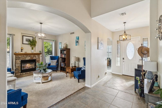 carpeted entryway with a chandelier and a stone fireplace