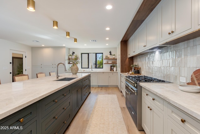 3186 E Stella Ln, Phoenix, AZ 85016 - kitchen featuring a sink, range with two ovens, decorative backsplash, light wood finished floors, and white cabinetry
