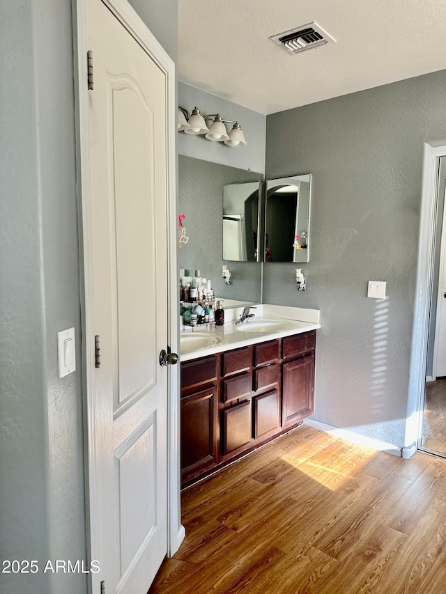 491 E Jeanne Ln, San Tan Valley, AZ 85140 - bathroom featuring wood finished floors, double vanity, a textured wall, and baseboards