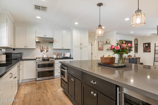 3308 N 51st St, Phoenix, AZ 85018 - kitchen with under cabinet range hood, stainless steel appliances, white cabinets, dark countertops, and recessed lighting