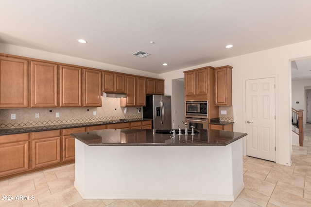 kitchen featuring sink, an island with sink, dark stone counters, and appliances with stainless steel finishes