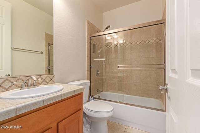 full bathroom with shower / bath combination with glass door, vanity, tile patterned floors, and toilet