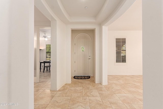 entrance foyer with a tray ceiling and ceiling fan