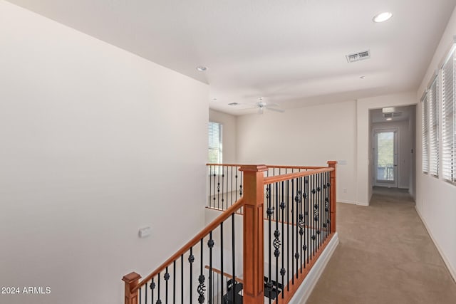 corridor with light colored carpet and a healthy amount of sunlight