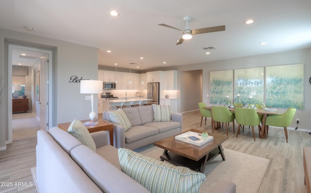 living room with ceiling fan and light hardwood / wood-style flooring