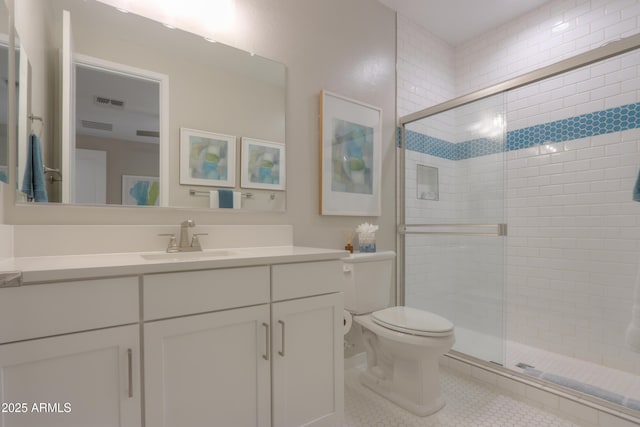 bathroom featuring tile patterned flooring, vanity, a shower with shower door, and toilet