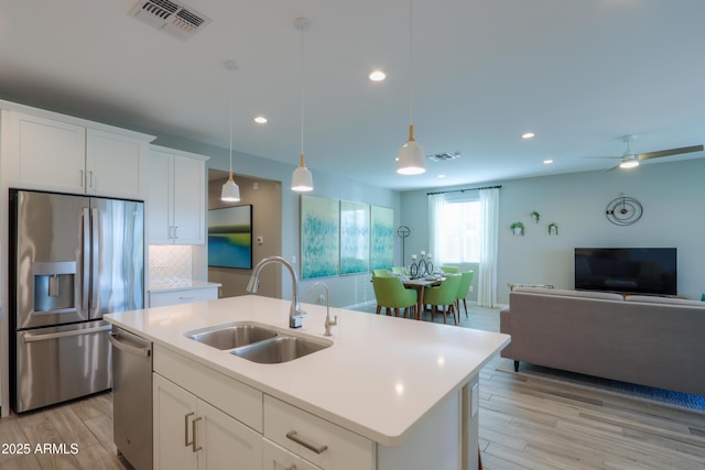 kitchen with sink, stainless steel appliances, an island with sink, and white cabinets