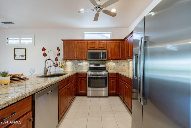 kitchen with sink, light tile patterned floors, appliances with stainless steel finishes, light stone countertops, and backsplash