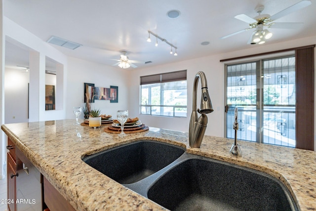 kitchen featuring light stone counters, sink, track lighting, and ceiling fan