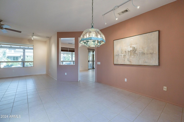 spare room with light tile patterned flooring, rail lighting, and ceiling fan with notable chandelier